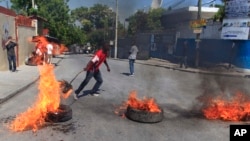 A protester supporter of presidential candidate Moise Jean-Charles, of the Platform Petit Dessalines political party sets fire to a tire during a protest in Port-au-Prince, Haiti, Thursday, Oct. 29, 2015.