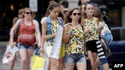 FILE - Consumers hold shopping bags as they walk along Michigan Avenue, July 29, 2016 in Chicago, Illinois. 