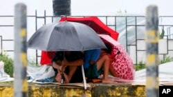 Warga berlindung di balik paying mereka sementara angin kencang dan hujan turun akibat Topan Koppu, 18 Oktober 2015 di Manila, Filipina. 