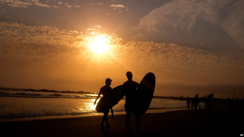 资料照片：加利福尼亚州洛杉矶威尼斯海滩夕阳下的冲浪者。(2021年6月16日)(photo:VOA)