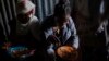 FILE - Displaced Tigrayan women, one wearing an Ethiopian Orthodox Christian cross, sit in a metal shack to eat food donated by local residents at a reception center for the internally displaced in Mekele, in the Tigray region of northern Ethiopia, on May