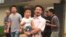 This image taken from video shows Chinese labor activists Hua Haifeng, center, carrying his son, Bobo, and Li Zhao, second from left, leaving a police station after being released in Ganzhou in southern China's Jiangxi province, June 28, 2017. Chinese authorities have released three activists, including Hua and Li, who had been detained after investigating labor conditions at a factory that produced shoes for Ivanka Trump and other brands.
