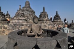 Tourists inspect a Buddha statue at Borobudur Temple in Magelang, Central Java, Indonesia, Aug. 12, 2019.