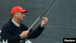 FILE - Former England cricketer Ian Botham casts his line on Loch Tay at Kenmore, on the opening day of the salmon season, Jan. 15, 2001.