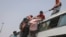 FILE - Indians load a motorcycle on the roof of a bus carrying migrant workers, who are leaving the capital during the COVID pandemic, in New Delhi, India, June 16, 2020.