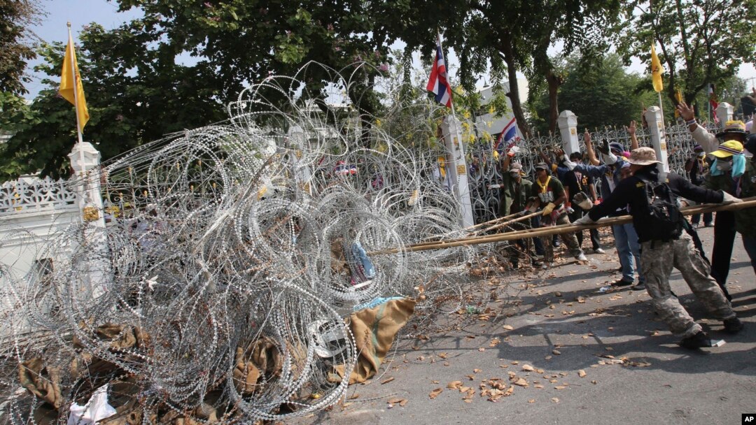 Demo anti-pemerintah memindahkan pagar kawat berduri di kantor PM (yang dikenal dengan sebutan Government House) di Bangkok, Thailand (12/12).