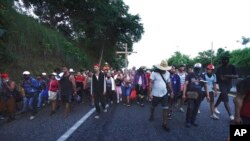 Sekelompok migran bergerak menuju ke utara menyusuri area pesisir Huixtla, Meksiko, pada 25 Oktober 2021. Mereka sebelumnya menunggu di Tapachula untuk memproses permintaan suaka namun akhirnya pergi meninggalkan proses tersebut karena telah lama menunggu. (Foto: AP/Marco Ugarte)