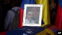 A framed portrait of opposition activist Fernando Alban shadowed by an image of Jesus Christ sits on the flag-draped casket containing his remains, during a solemn ceremony at the National Assembly headquarters, Caracas, Venezuela, Oct. 9, 2018. 