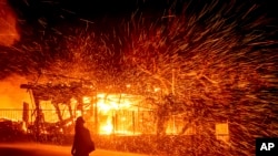 A firefighter passes a burning home as the Hillside fire burns in San Bernardino, California, Oct. 31, 2019. 
