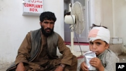 FILE - A boy who was injured boy in a deadly attack on a market sits on the ground at a hospital in Helmand province, June 29, 2020.