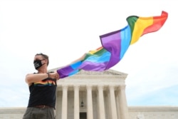 Joseph Fons holding a Pride Flag, stands in front of the U.S. Supreme Court building after the court ruled that a federal law banning workplace discrimination also covers sexual orientation, in Washington, D.C., June 15, 2020.