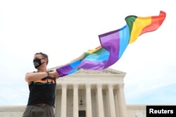 Joseph Fons holding a Pride Flag, stands in front of the U.S. Supreme Court building after the court ruled that a federal law banning workplace discrimination also covers sexual orientation, in Washington, D.C., June 15, 2020.