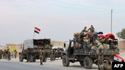 Military vehicles transporting Syrian regime troops and rolled up mattresses are stationed on the outskirts of the northern Syrian border town of Kobani on Oct. 16, 2019. 