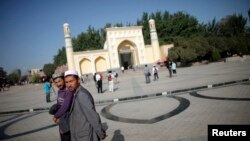 Warga Uighur berjalan di depan masjid di Kashgar, propinsi Xinjiang (Foto: dok). Pengadilan di daerah ini dilaporkan telah menjatuhkan hukuman penjara atas 19 warga Uighur dengan tuduhan menghasut ekstrimisme agama.