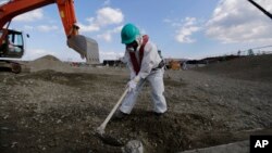 A worker, wearing a protective suit and a mask, levels ground at the tsunami-crippled Fukushima Dai-ichi nuclear power plant, operated by Tokyo Electric Power Co. (TEPCO), in Okuma, Fukushima Prefecture, northeastern Japan, Wednesday, Feb. 10, 2016.