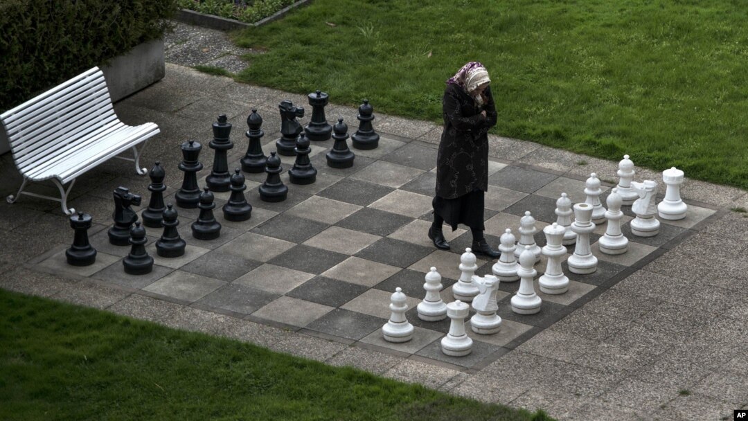 FILE - A member of the Iranian media walks on an open air chess board at the site of negotiations about Iran's nuclear program, between Iran officials and representatives of the world powers, Monday March 30, 2015 in Lausanne, Switzerland.