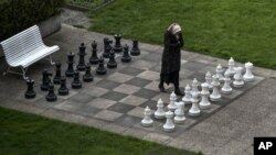 FILE - A member of the Iranian media walks on an open air chess board at the site of negotiations about Iran's nuclear program, between Iran officials and representatives of the world powers, Monday March 30, 2015 in Lausanne, Switzerland.