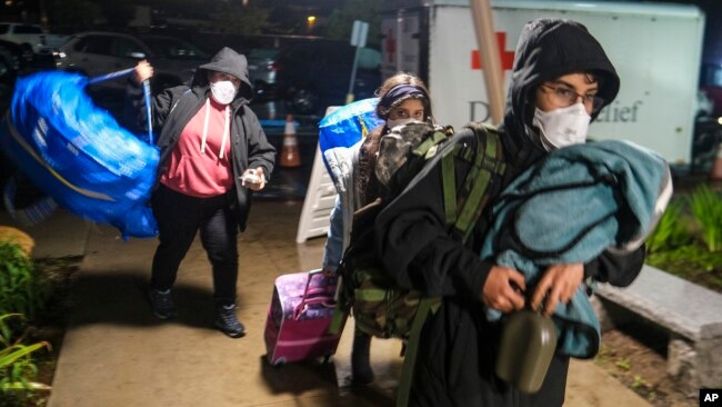 People carrying their belongs arrive at an evacuation center in Santa Barbara, California, Jan. 9, 2023.