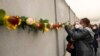 ARCHIVO - Un estudiante coloca una flor en los restos del Muro de Berlín durante una ceremonia conmemorativa para celebrar el 32º aniversario de su caída en Berlín, Alemania, el 9 de noviembre de 2021.