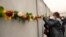 ARCHIVO - Un estudiante coloca una flor en los restos del Muro de Berlín durante una ceremonia conmemorativa para celebrar el 32º aniversario de su caída en Berlín, Alemania, el 9 de noviembre de 2021.