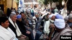 Neighbors and friends of relatives of the Egyptian Coptic men killed in Libya sit at the courtyard of the Virgin Mary Church in the village of el-Aour, near Minya, 220 kilometers (135 miles) south of Cairo, Egypt, Feb. 16, 2015.