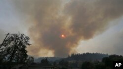 A plume of smoke rises from a mountain over homes in the Oakmont area of Santa Rosa, Calif., Oct. 10, 2017.