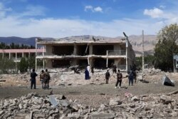 FILE - Afghan security personnel inspect the site of a car bomb blast near the destroyed office building of Afghanistan's intelligence agency in the city of Aybak on July 13, 2020. The attack was claimed by the Taliban, officials said.