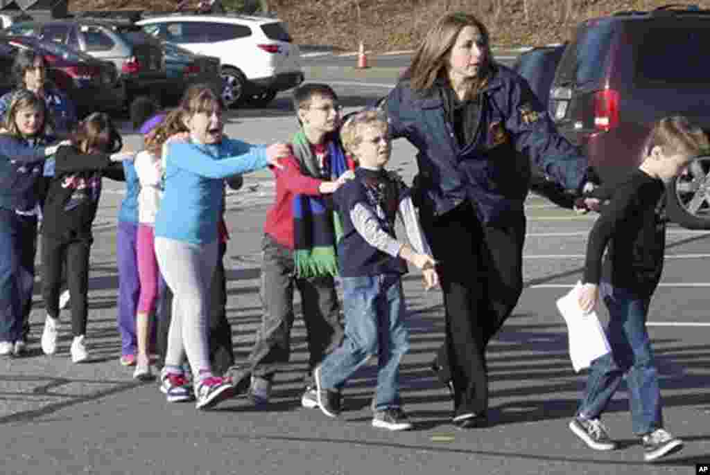 In this photo provided by the Newtown Bee, Connecticut State Police lead children from the Sandy Hook Elementary School in Newtown, Conn., following a reported shooting there, Dec. 14, 2012.