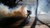 A protester retrieves a tear gas canister from security forces blocking an opposition march from reaching the National Electoral Council headquarters in Caracas, Venezuela, May 24, 2017. 