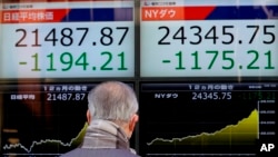 A man looks at an electronic stock indicator of a securities firm in Tokyo, Japan, Feb. 6, 2018.