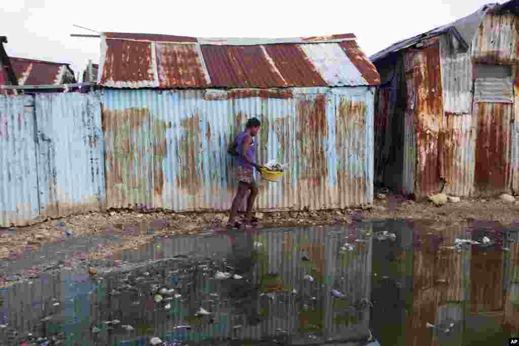 Una mujer en un barrio pobre de Puerto Príncipe, Haití, salta una poza de agua de camino a casa, en la víspera de que el catastrófico huracán Irma llegue a la isla. AP Sept.6, 2017.