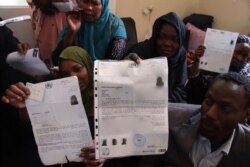 Asylum seekers from Sudan in Libya hold up documents from the United Nations, insisting that they have the right to flee their country, April 29, 2019. (H.Murdock/VOA)