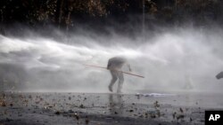 Protester tries to evade spray from police water cannon, Santiago, Chile, June 25, 2015.