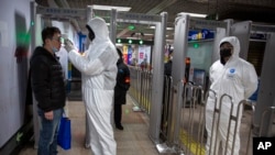 Nhân viên y tế ở Trung Quốc kiểm tra thân nhiệt hành khách tại một nhà ga tàu điện.