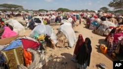 Drought-stricken Somalis walk through a camp in the Garasbaley area on the outskirts of Mogadishu, Somalia, March 28, 2017. 