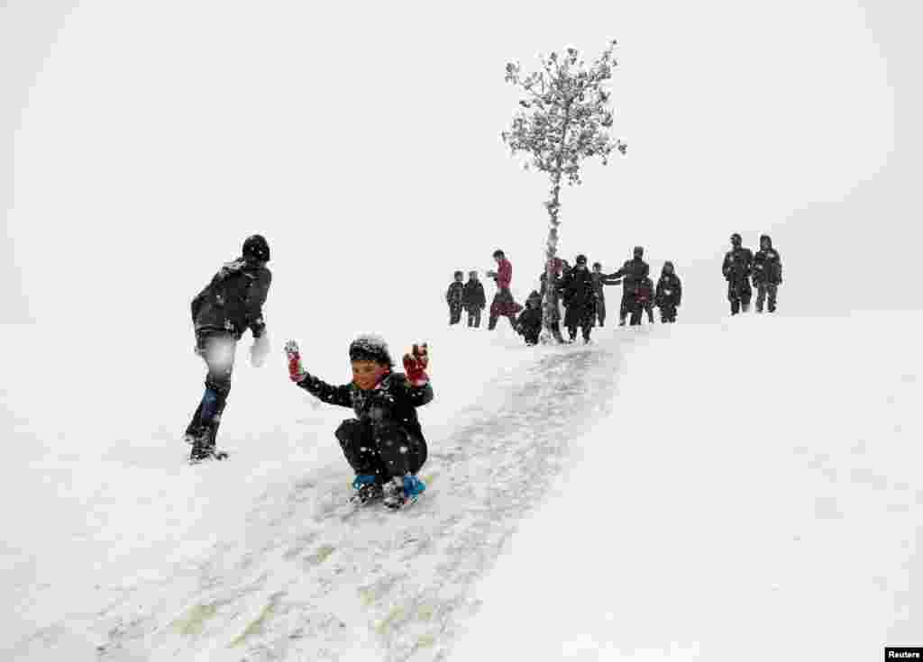 Afghan boys slide down a snow-covered slope in Kabul.