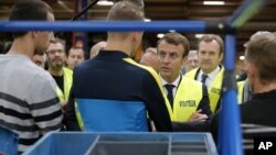 French President Emmanuel Macron, center right, talks with Whirlpool employees during a visit of the Whirlpool factory in Amiens, Oct. 3, 2017. 