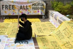 FILE - A supporter of pro-democracy activists holds a sign outside West Kowloon Magistrates' Courts where others queue up for a court hearing over charges related to national security, in Hong Kong, China, March 1, 2021.