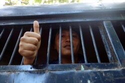 FILE - Moe Thway, one of the activists who protested against a controversial copper mine project, gives thumbs-up sign from police truck as he leaves a township court with other activists on Nov. 22, 2013, in Yangon Myanmar.