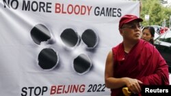 FILE - A Tibetan monk stands in front of a banner outside the Beijing 2022 Winter Olympic Games Bid presentation at the Palace Hotel in Lausanne, Switzerland June 10, 2015.