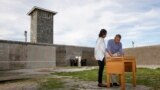 U.S. President Barack Obama writes in a guest book as he tours Robben Island with first lady Michelle Obama, near Cape Town, June 30, 2013. 