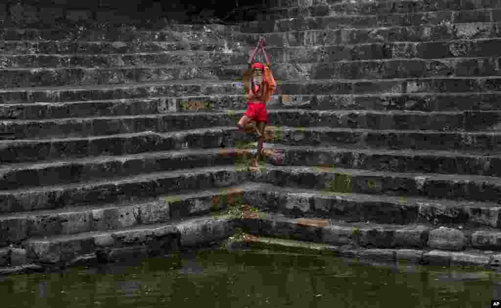 Seorang Sadhu atau orang suci Hindu melakukan yoga di tangga Saubhagya Kund, sebuah kolam suci di kuil Kamakhya di Gauhati, India.