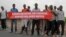 Young men hold a banner on the road that the convoy of the United Nations Security Council delegation took in Bujumbura, Burundi, Jan. 21, 2016. 