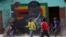 FILE: Children play soccer next to a defaced portrait of Former Zimbabwean President Robert Mugabe in Harare, Friday, Sept, 6 2019. 