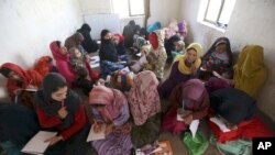 FILE- In this Oct. 30, 2017, photo, internally displaced Afghan girls and women study at a class near their temporary homes on the outskirts of Kabul.