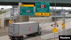 FILE - A commmercial truck exits the highway for the Ambassador Bridge to Canada, in Detroit, Michigan, Aug. 30, 2018. 