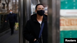 A man wearing a face mask looks at a board at a bus stop, as the country is hit by an outbreak of the new coronavirus, in Beijing, China January 27, 2020.
