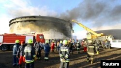 Firefighters work to put out a fire at a storage oil tank in the port of Es Sider, Jan. 2, 2015. 