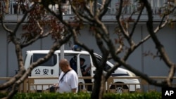 FILE - A man walks by a police van in Beijing, China, June 4, 2024.