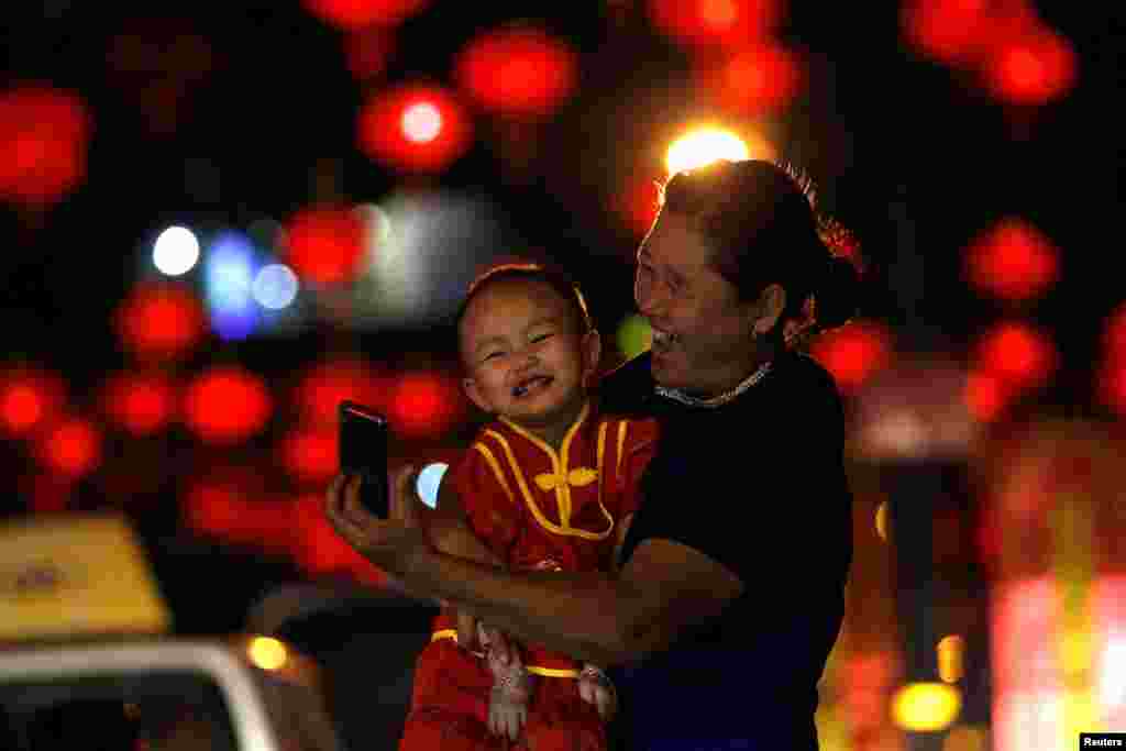 Seorang ibu dan anaknya mengambil swafoto di jalan yang dihiasi lampion China untuk merayakan Tahun Baru Imlek di Yangon, Myanmar (25/1). (Reuters/Soe Zeya Tun)